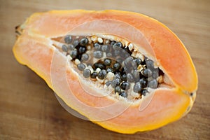 Fresh organic ripe papaya fruit cut in half on a wooden board. Exotic fruits, healthy eating concept