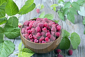 Fresh organic ripe raspberry with leaf in bowl on wooden table photo