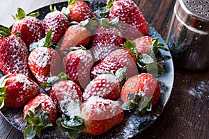 Fresh Organic Ripe Strawberries with Powdered Sugar on Black Plate.