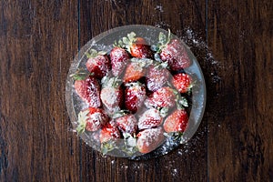 Fresh Organic Ripe Strawberries with Powdered Sugar on Black Plate.