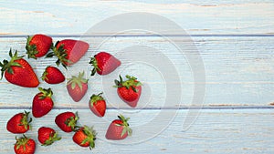 Fresh and organic strawberries fall from the top of wooden table - Stop motion