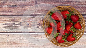 Fresh and organic strawberries filling wooden basket on wooden table - Stop motion