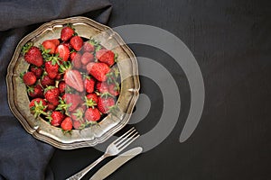 Fresh organic strawberry in vintage plate on black table. Space for you. Summer.