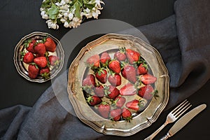 Fresh organic strawberry in vintage plate on black table. Spring.