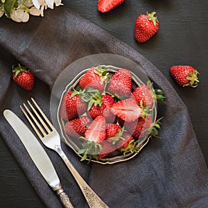 Fresh organic strawberry in vintage plate on black table. Summer.