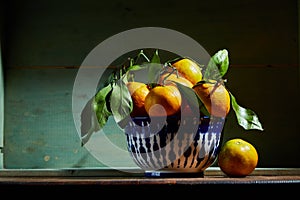 Fresh organic tangerines with leaves in bowl in bright sunlight with copy space. Still life with natural tropical fruit photo