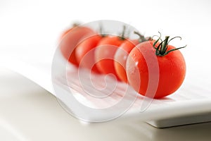 Fresh organic tomatoes on a white ceramic plate