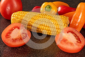 Fresh organic vegetable mix with tomatoes, bell peppers, and corn on black background