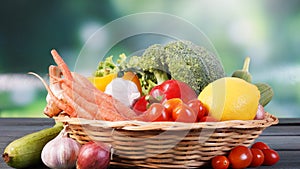 Fresh organic vegetables in basket on table and blur green background, Healthy food concept.