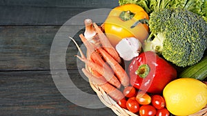 Fresh organic vegetables in basket on wooden table top view. Healthy food concept.