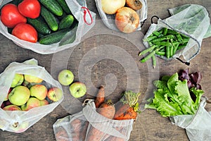 Fresh organic vegetables, fruits and greens in reusable recycled mesh produce bags on wooden background with copy space. Zero