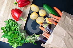 Fresh organic vegetables spilling out of paper shopping bag
