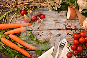 Fresh organic vegetables and spoons on rustic wooden background, top view, border. Healthy food or vegetarian cooking