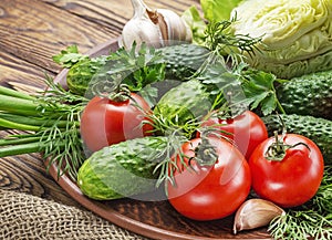 Fresh organic vegetables tomatoes, onions, cucumbers in a plate