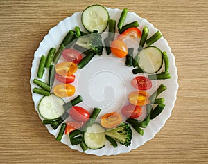 Fresh Organic Vegetables on wooden Table Around White Plate with copy space for your text.