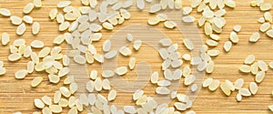 Fresh organic white raw rice grains texture, on bamboo cutting board