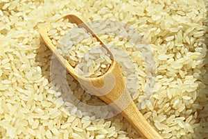 Fresh organic white raw rice grains texture and wooden spoon, uncooked rice background