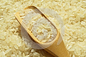 Fresh organic white raw rice grains texture and wooden spoon, uncooked rice background