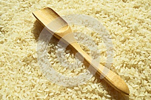 Fresh organic white raw rice grains texture and wooden spoon, uncooked rice background