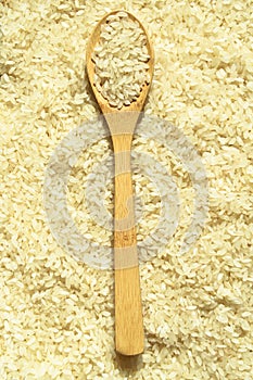 Fresh organic white raw rice grains texture and wooden spoon, uncooked rice background