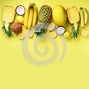 Fresh organic yellow fruits over sunny background. Monochrome concept with banana, coconut, pineapple, lemon, melon. Top