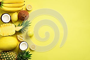 Fresh organic yellow fruits over sunny background. Monochrome concept with banana, coconut, pineapple, lemon, melon. Top