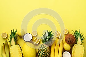 Fresh organic yellow fruits over sunny background. Monochrome concept with banana, coconut, pineapple, lemon, melon. Top