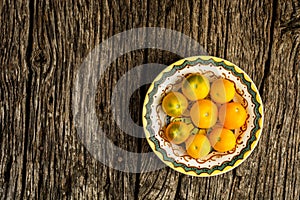 Fresh, organic yellow tomatoes on yellow plate over rustic wooden background with copy space. Flat lay