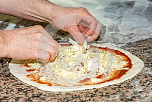 Fresh original Italian raw pizza, dough preparation in traditional style: the chef distributes the cheese. Food, italian cuisine a