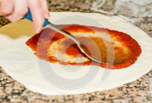 Fresh original Italian raw pizza, dough preparation in traditional style. the chef spreads the tomato sauce. Food, italian cuisine