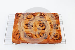 Fresh from the oven chelsea buns on a wire cooling rack - viewed