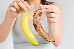 Fresh and overripe bananas on woman hand