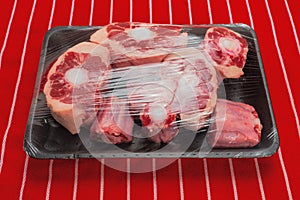 Fresh ox tail portions on a black plastic trey wrapped in plastic