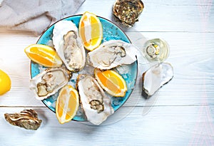 Fresh oysters close-up on blue plate, served table with oysters, lemon and champagne in restaurant. Gourmet food