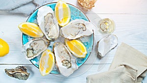 Fresh oysters close-up on blue plate, served table with oysters, lemon and champagne in restaurant. Gourmet food