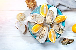 Fresh oysters close-up on blue plate, served table with oysters, lemon and champagne in restaurant. Gourmet food