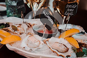 Fresh Oysters close up on a plate, served table with oysters, lemon and ice. Healthy sea food.
