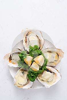 Fresh oysters in a white plate with ice and lemon on a wooden de