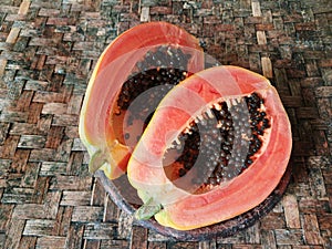 Fresh papaya cut open on a wooden surface. Papaya halves on wood