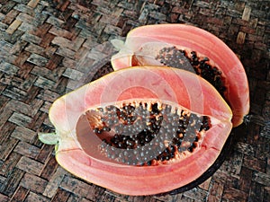 Fresh papaya cut open on a wooden surface. Papaya halves on wood