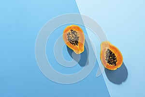 Fresh papaya fruit cut in half on blue background. Tropical fruit