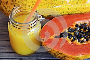 Fresh papaya juice in a glass jar ripe papaya fruit on old wooden table.Healthy drink,detox,diet or vegan food concept.