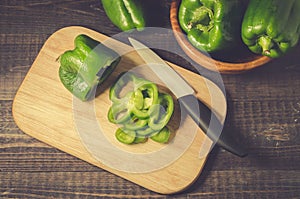 fresh paprika in a wooden bowl and cut on a board/ fresh paprika in a wooden bowl and cut on a board on a dark table, top view