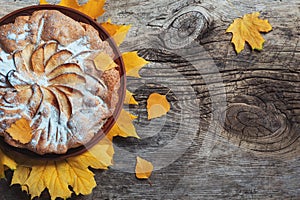 Fresh pastry apple pie charlotte on wooden table background decorated with yellow autumn leaves. Fall Food Cook Cuisine Homemade