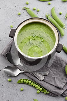 Fresh pea soup in bowl with spoons and napkin