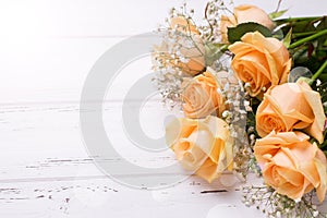 Fresh peach color roses flowers on white wooden background in ra