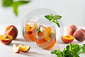 Fresh Peach iced tea. Iced tea with peach slices, mint and ice cubes on a white background. Close up. Homemade refreshing summer