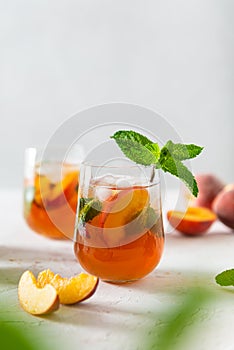 Fresh Peach iced tea. Iced tea with peach slices, mint and ice cubes on a white background. Close up. Homemade refreshing summer