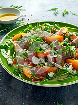 Fresh Peach salad with Parma ham, feta cheese and vegetables in a green plate. healthy food