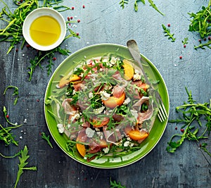 Fresh Peach salad with Parma ham, feta cheese and vegetables in a green plate. healthy food